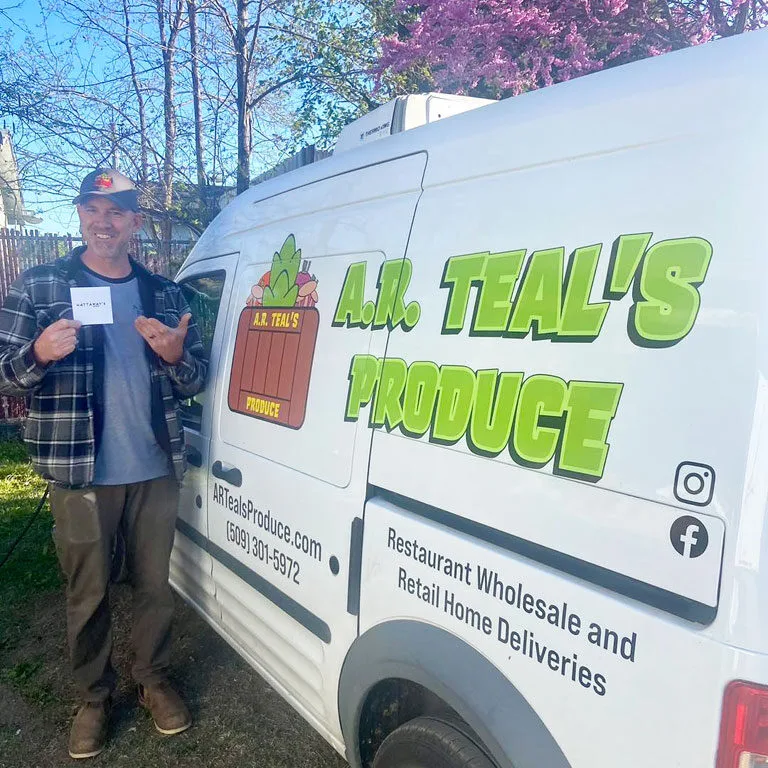 Cheerful man next to A.R. Teals Produce delivery van on a sunny spring day.
